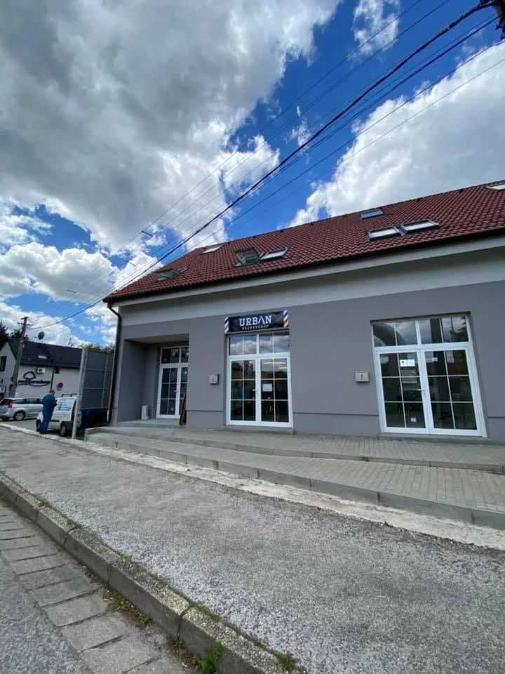 Prevádzka Urban Barbershop, sivá budova s červenou strechou a nápisom URBAN nad vchodom
